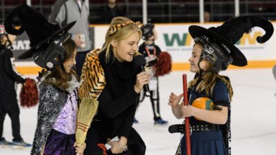Image of the 67's in game hostess talking with kids dressed in Halloween costumes