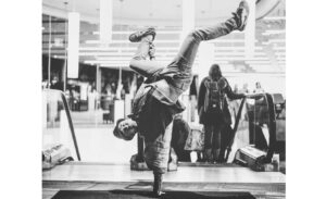 Image of breakdancer in a hand stand with his legs up in a pose