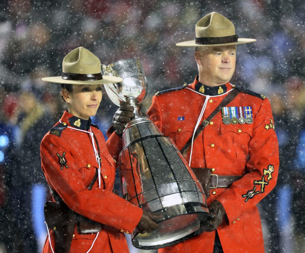 2 Canadian Mounties holding the Grey Cup