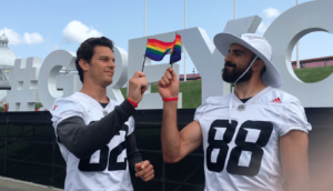 Two Redblacks players holding Pride flags