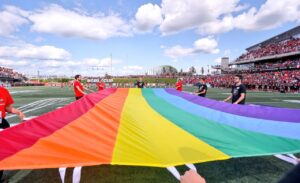 fans holding a rainbow Pride flag on the field at TD Place