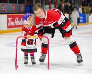 Image of a young fan skating along side a 67's player