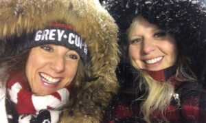 Image of 2 female REDBLACKS fans in winter coats on a snowy day