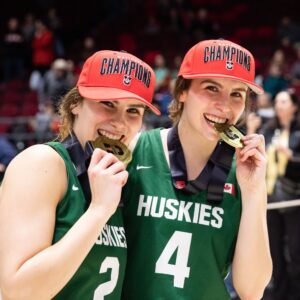 Image of 2 female basketball player posing with their gold medals from the U Sports Final 8 Tournament
