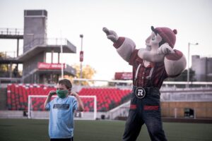 Image of Big Joe and a young kid posing on the field at TD place